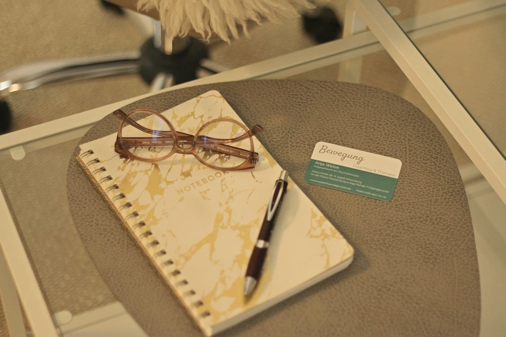 Notizblock mit Brille, Stift und Visitenkarte